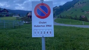 Un panneau indiquant l’interdiction de se garer, portant l’inscription « Chalet Hubertus 396d » et un tableau avec des numéros.