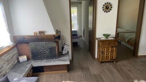 Une pièce chaleureuse avec une cheminée, un meuble en bois, un lit et une vue sur l’extérieur.