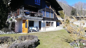 A two-story chalet with a balcony, a stone foundation, and a mountain backdrop. - Kaisers Ferienwohnung Appartement/Fewo 3-Bettwohnung by Interhome (Niederried)