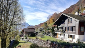 A traditional wooden house with a stone wall and a modern two-story building with balconies. - Kaisers Ferienwohnung Appartement/Fewo 3-Bettwohnung by Interhome (Niederried)