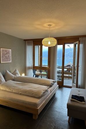 Une chambre à coucher comprenant un lit, une table de chevet, un luminaire suspendu et une vue sur l’extérieur.