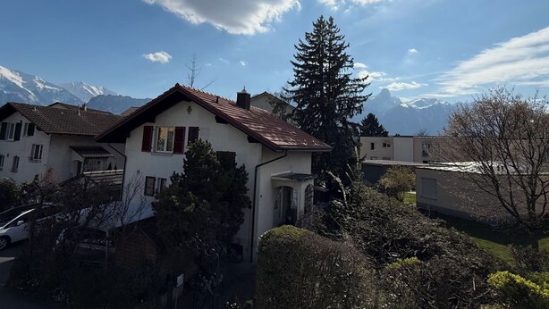 Ein Wohngebiet mit Häusern, einem Berg im Hintergrund und einem klaren Himmel.