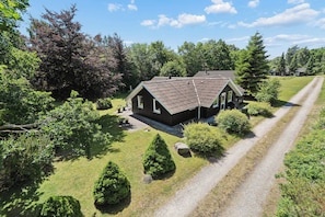 A house with a sloped roof, surrounded by a well-maintained lawn and trees. - Renovated, 4 rooms, sea view, beach, calm (Nysted)