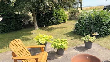 Una silla de madera y plantas en macetas en un patio con vistas al mar.