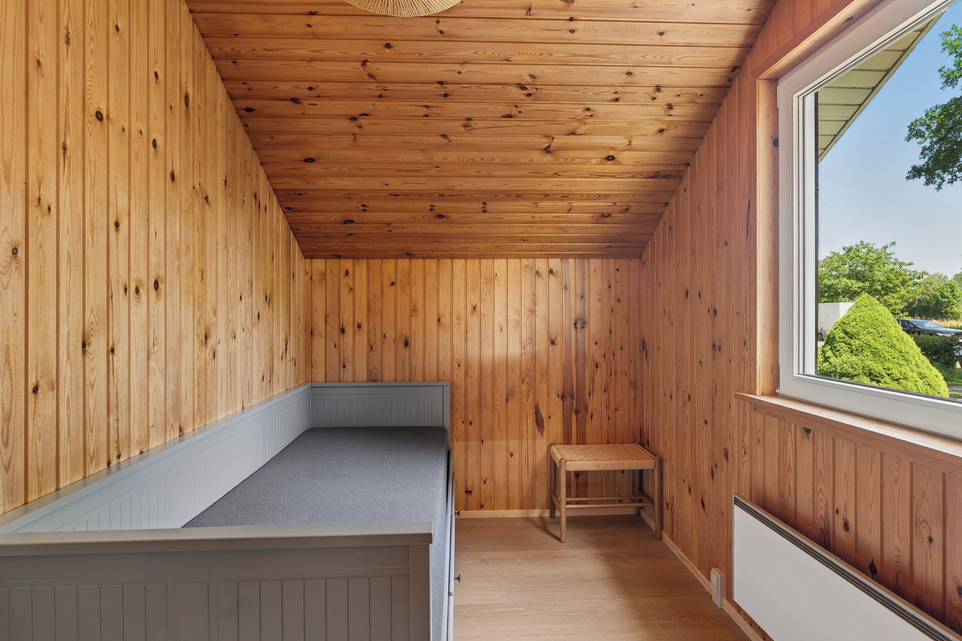 Una stanza con rivestimenti in legno, una panca, una finestra e un termosifone.