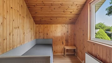 Una stanza con rivestimenti in legno, una panca, una finestra e un termosifone.