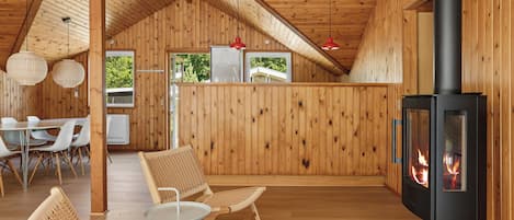 Un intérieur en bois avec une cheminée, des meubles en osier et un coin repas.