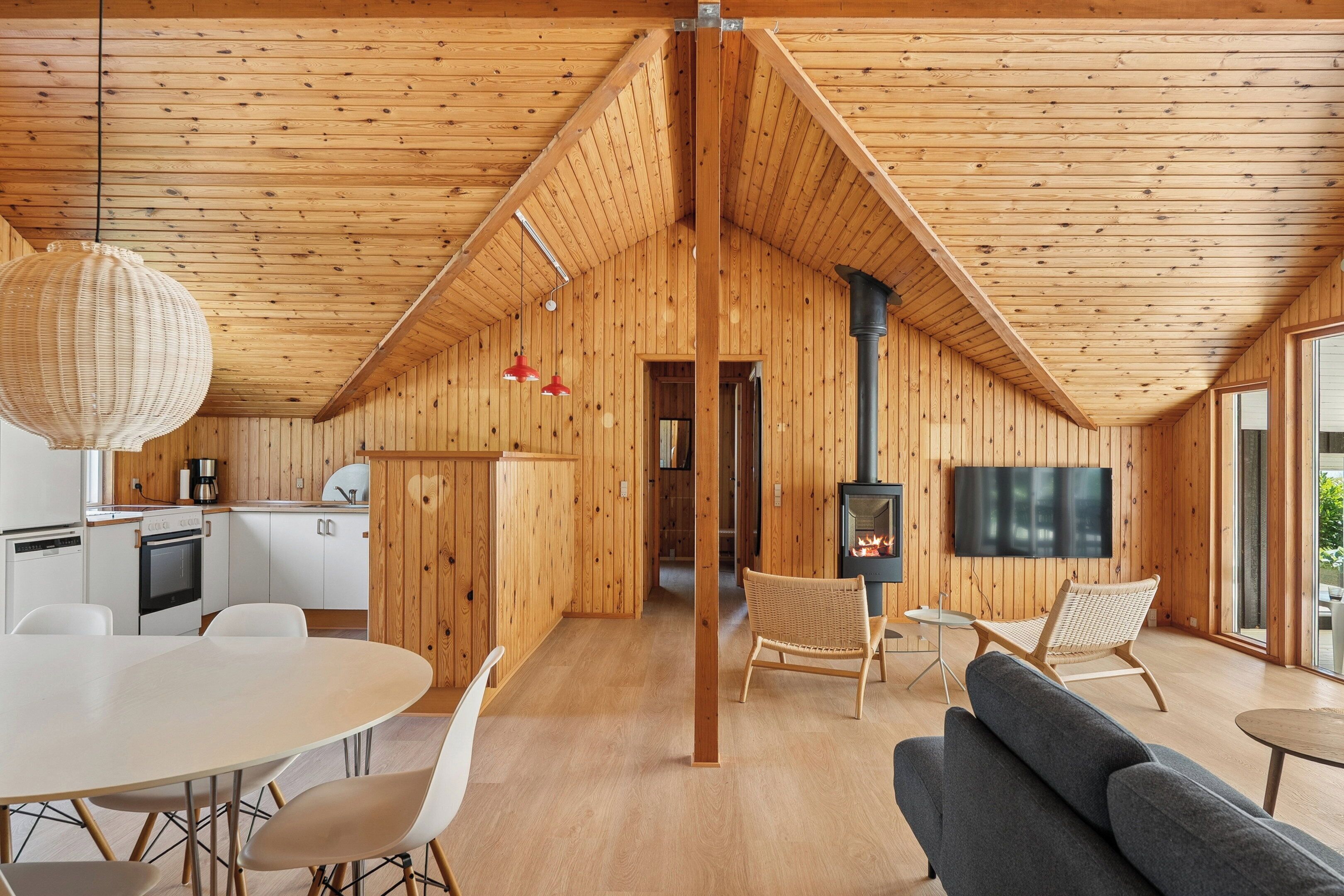 A wooden interior with a dining area, kitchen, and seating.