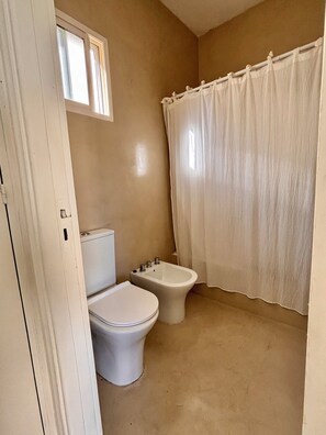 A bathroom with a toilet, bidet, and a shower curtain. - Meraki: Bright & Cozy | Walk Everywhere (Buenos Aires)