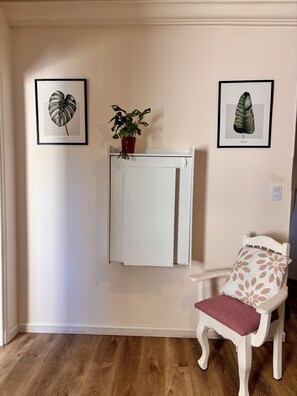 A room with a white cabinet, a chair with a patterned cushion, and two framed botanical prints on the wall. - Meraki: Bright & Cozy | Walk Everywhere (Buenos Aires)