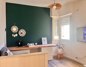A room with a dark green accent wall, a wooden desk with a coffee machine, a small potted plant, and a framed picture. - Meraki: Bright & Cozy | Walk Everywhere (Buenos Aires)