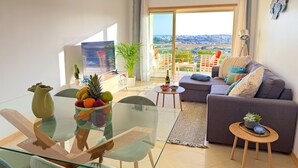 Un soggiorno moderno con un tavolo da pranzo in vetro, un divano e un balcone con vista.