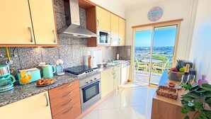 Una cucina moderna con piani in granito, elettrodomestici in acciaio inossidabile e vista sulla città tramite una porta scorrevole in vetro.