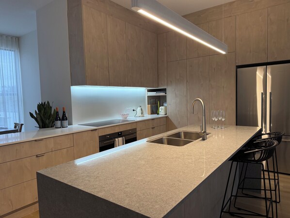 Een moderne keuken met een groot eiland, roestvrijstalen apparatuur en een minimalistisch design.