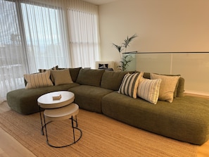 A modern living room with a sectional sofa, a round coffee table, and a small side table. - 100m to Aldinga Beach - Stunning new townhouse. (Aldinga Beach)