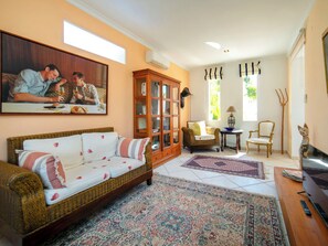Ein Wohnzimmer mit einer Couch, einem Schrank, einem Fernseher und einem Gemälde an der Wand.