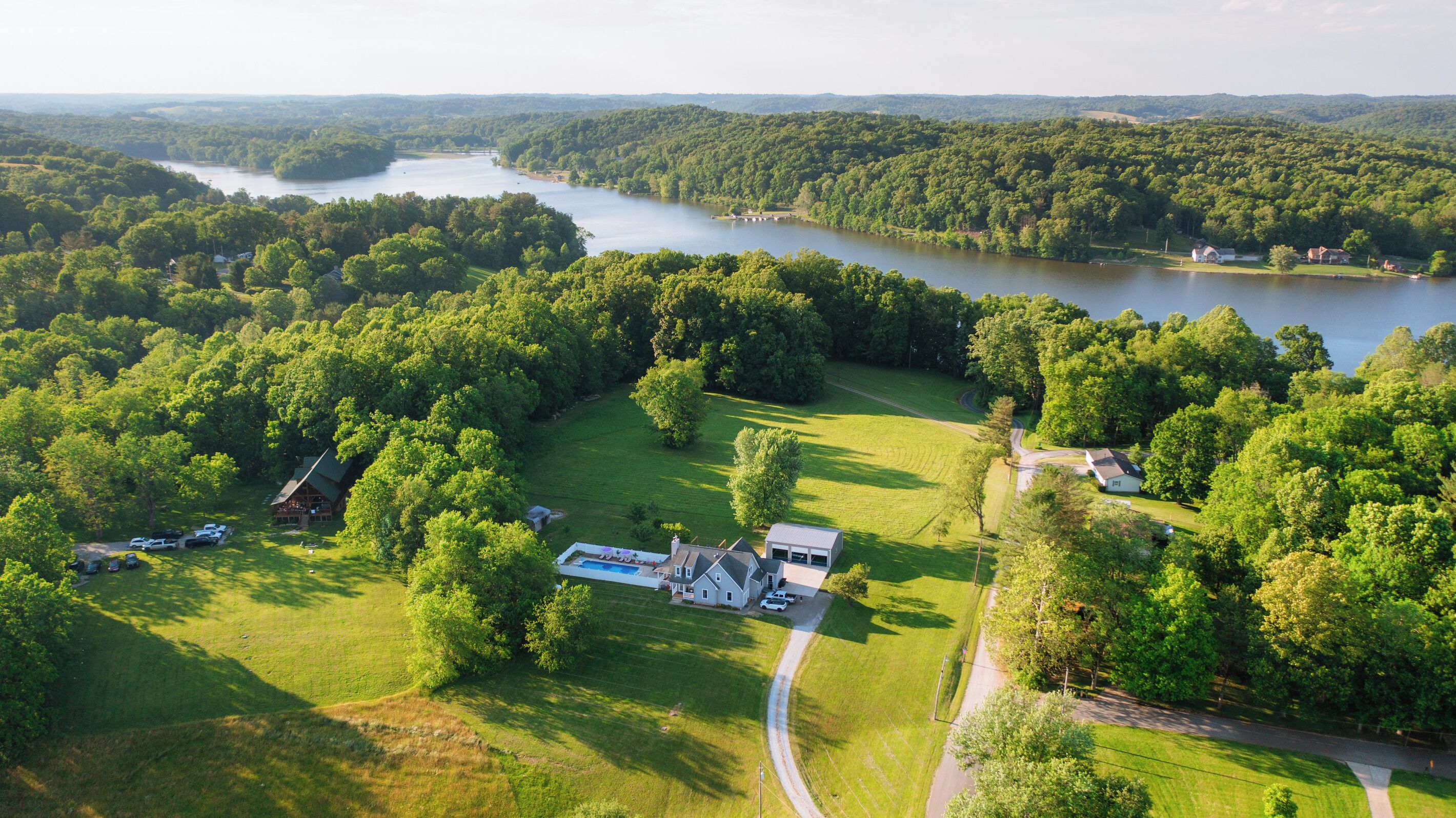 Vista aérea de una propiedad con una casa grande, piscina y un lago.