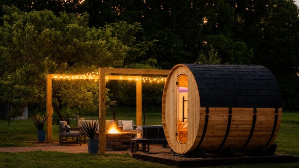 Een houten constructie met een vuurkuil en zithoek, omringd door lichtslingers.