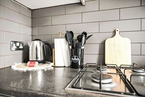 Eine Küche mit Gasherd, Wasserkocher, Toaster, Papierhandtuchhalter und Schneidebrett.