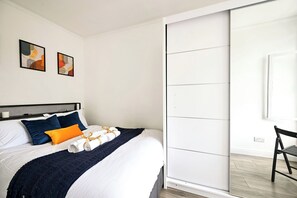 Ein modernes Hotelzimmer mit einem Bett, einer Schiebetür, einem Sessel und einem Bild an der Wand.