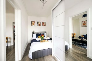 Une chambre d’hôtel avec un lit, une table de chevet, un miroir et une vue sur le couloir.
