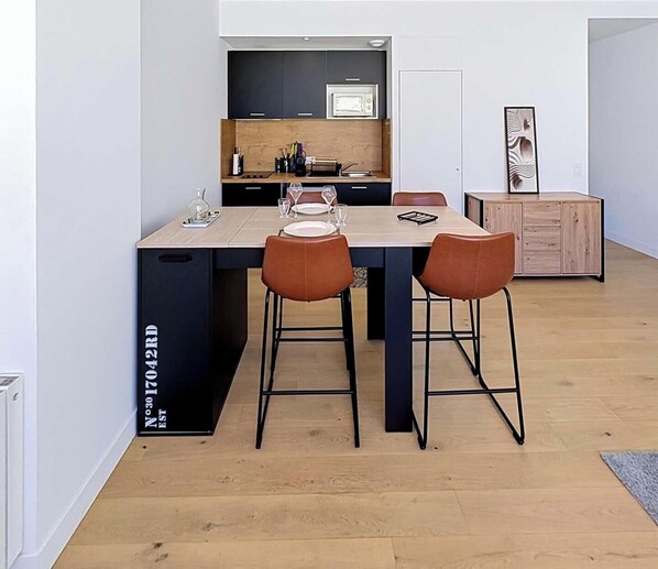 Una cocina moderna con armarios oscuros, encimera de madera y dos taburetes de bar.