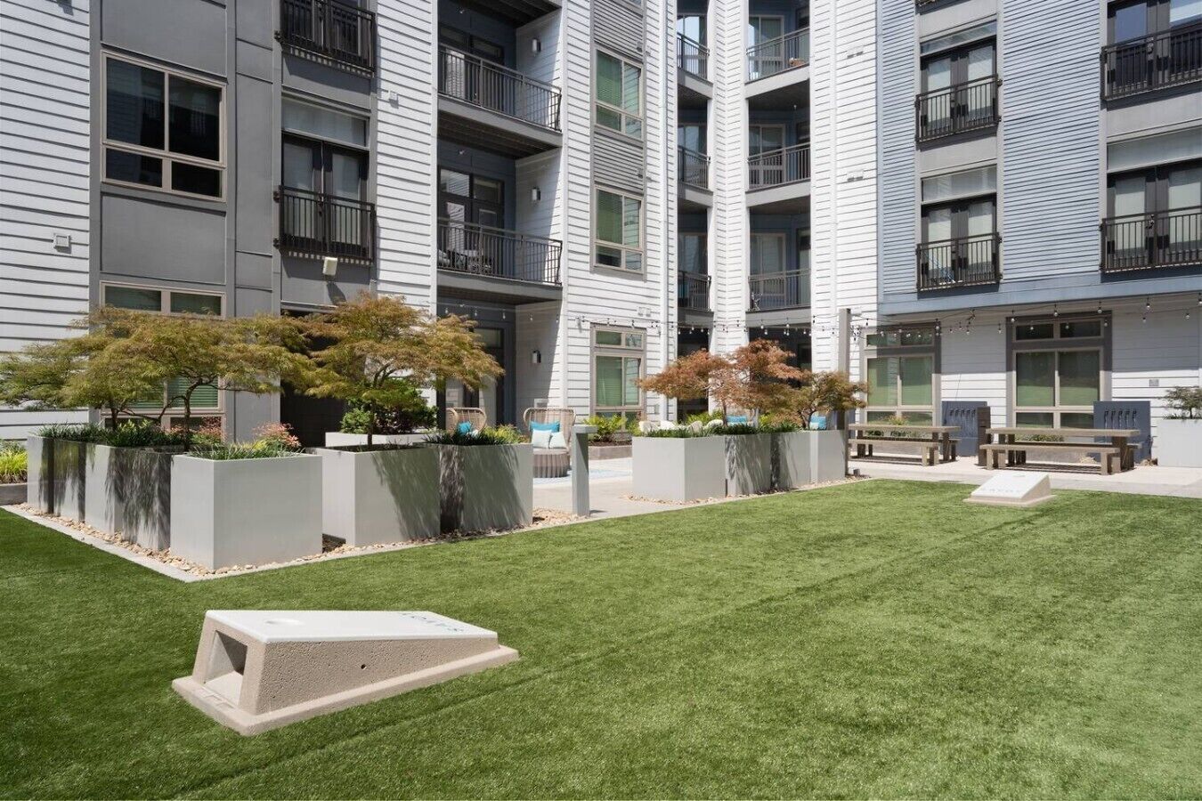 Un immeuble d’appartements moderne doté d’une pelouse bien entretenue, d’un espace extérieur aménagé et de grandes fenêtres.