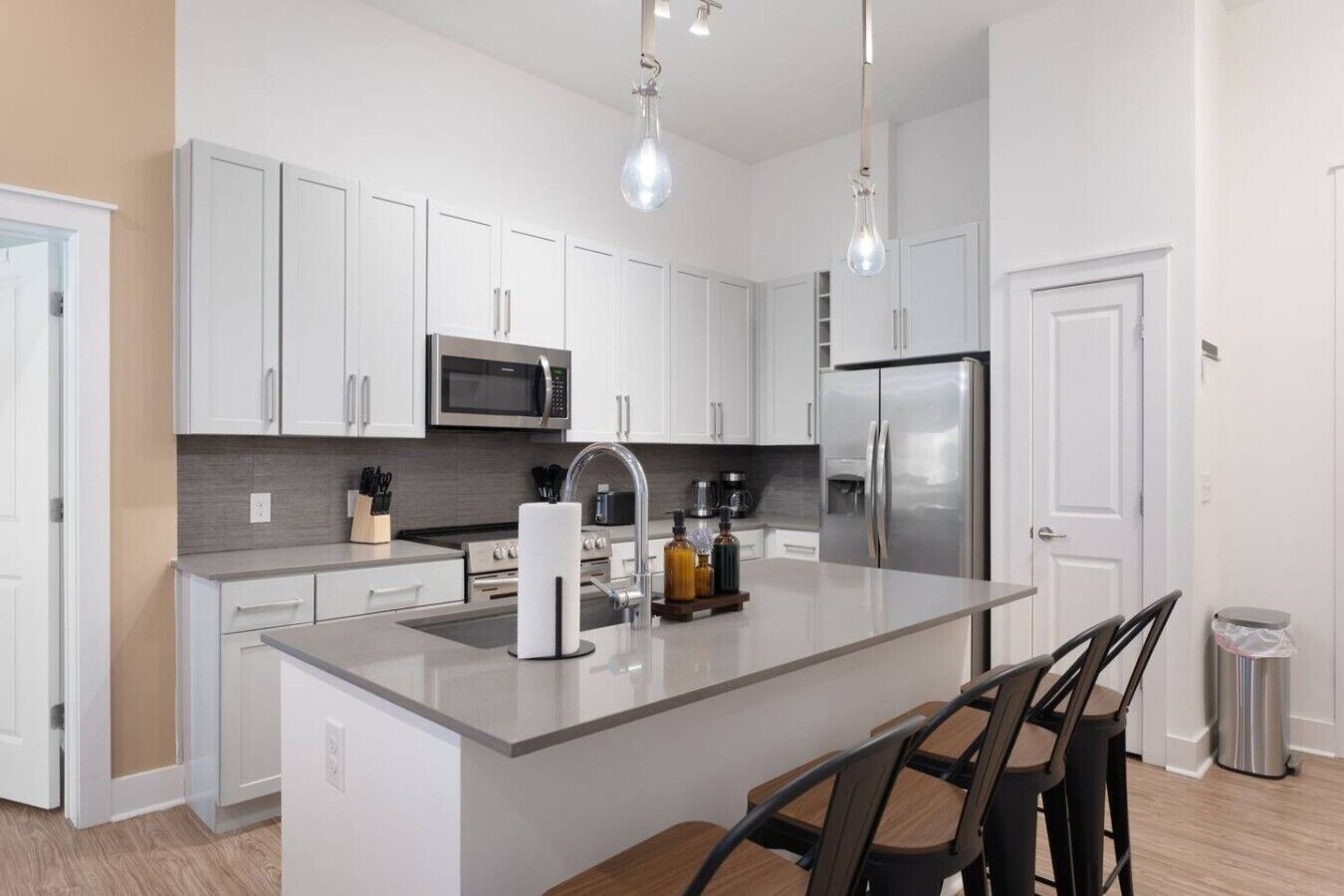 A modern kitchen with white cabinets, stainless steel appliances, and a central island with bar stools.