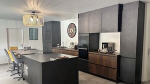 A modern kitchen with a central island, dark cabinetry, and a clock on the wall.