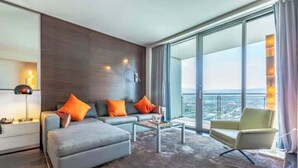 A modern living room with a sofa, ottoman, and armchair, a coffee table, and a large window with a view of the city. - 50th Floor Luxury Spa Suite at Palms Place (Las Vegas)