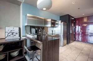 A modern kitchen with stainless steel appliances, a wooden island, and a dark-toned refrigerator.