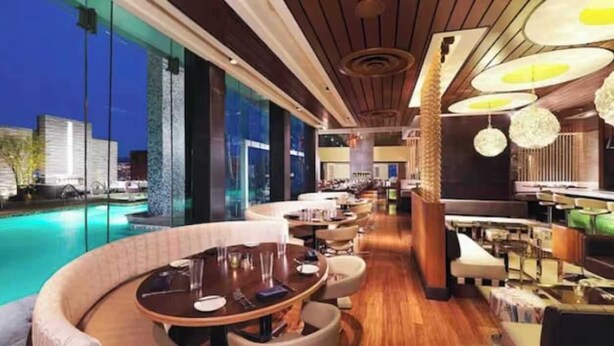 A poolside bar area with tables and chairs, a pool, and a view of buildings. - 50th Floor Luxury Spa Suite at Palms Place (Las Vegas)
