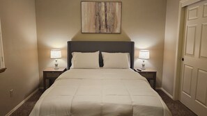 A hotel room with a bed, two bedside tables with lamps, a headboard, and a painting on the wall. - Spacious 4bd 3bth NW Home with AC (Bakersfield)