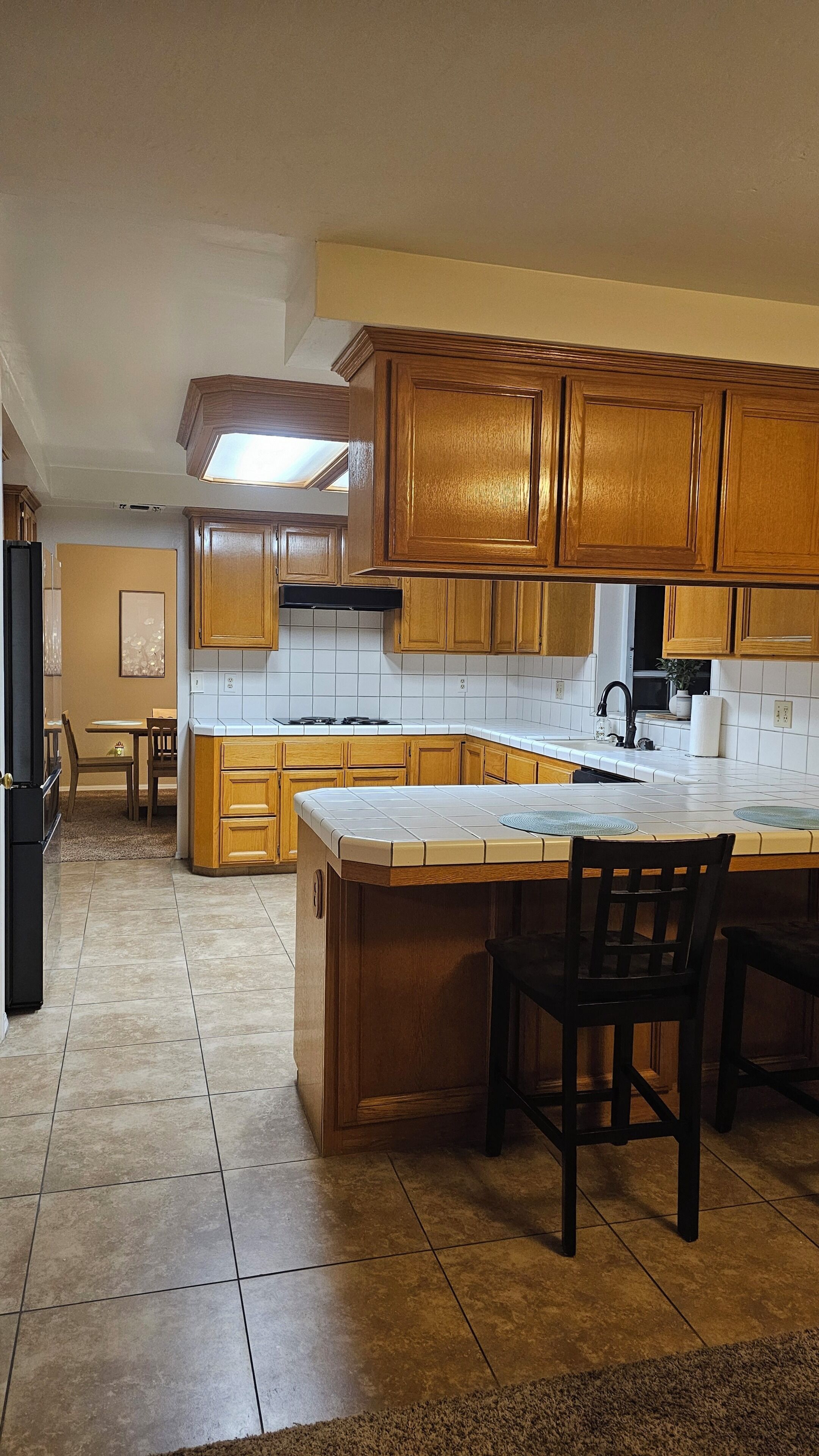 A kitchen with wooden cabinets, a large island, and a dining area with chairs.