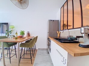 A modern kitchen with a wooden countertop, a sink, and a built-in oven. There is a dining area with a table and chairs. - Le Tiercé by Interhome (Cagnes-sur-Mer)