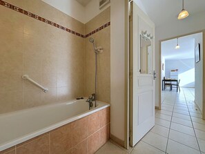 Ein Badezimmer mit einer Badewanne, einer Dusche und einer Handstange.