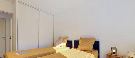 Ein Hotelzimmer mit zwei Betten, einem Kleiderschrank, einem Nachttisch mit Lampe und einem Teddybären.
