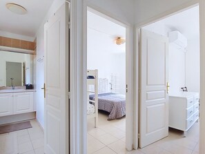 Ein Schlafzimmer mit Bett, Kommode und einem Badezimmer mit Waschbecken und Spiegel.