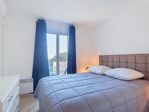A bedroom with a bed, a dresser, and a window with curtains. - Les Grenadines by Interhome (Les Issambres)