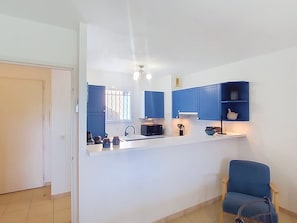 Een moderne keuken met blauwe kastjes, een magnetron en een spoelbak.