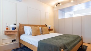Une chambre à coucher moderne avec un lit en bois, une literie blanche et un plaid vert.