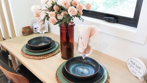 Een eettafel met een bloemenvaas, een wijnglas en een bord met een citaat.