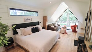 Een slaapkamer met een groot bed, een bank, een televisie en een raam.