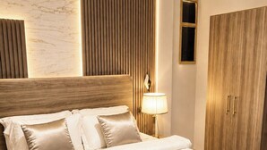 Una cama bien hecha con cabecera, una lámpara de noche y un armario de madera.