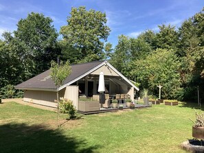 Ein eingeschossiges Gebäude mit einer Veranda und einem überdachten Sitzbereich im Freien.