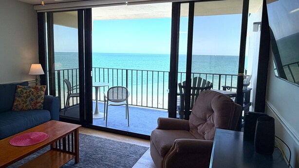 A room with a sofa, a chair, a small table, a TV, and a balcony with a view of the sea. - Posh Piper: 2BD, 2BA Oceanfront Condo in Royal Garden Resort, Garden City (Murrells Inlet)