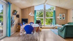Interior acolhedor de uma cabana com área de jantar, sofá e televisão.