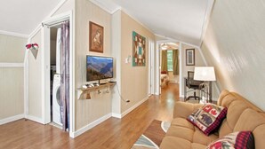 A living room with a sofa, a television, a washing machine, and a dining area with a table and chairs. - Romantic Mountain Retreat with Fenced Yard & Views (Creston)