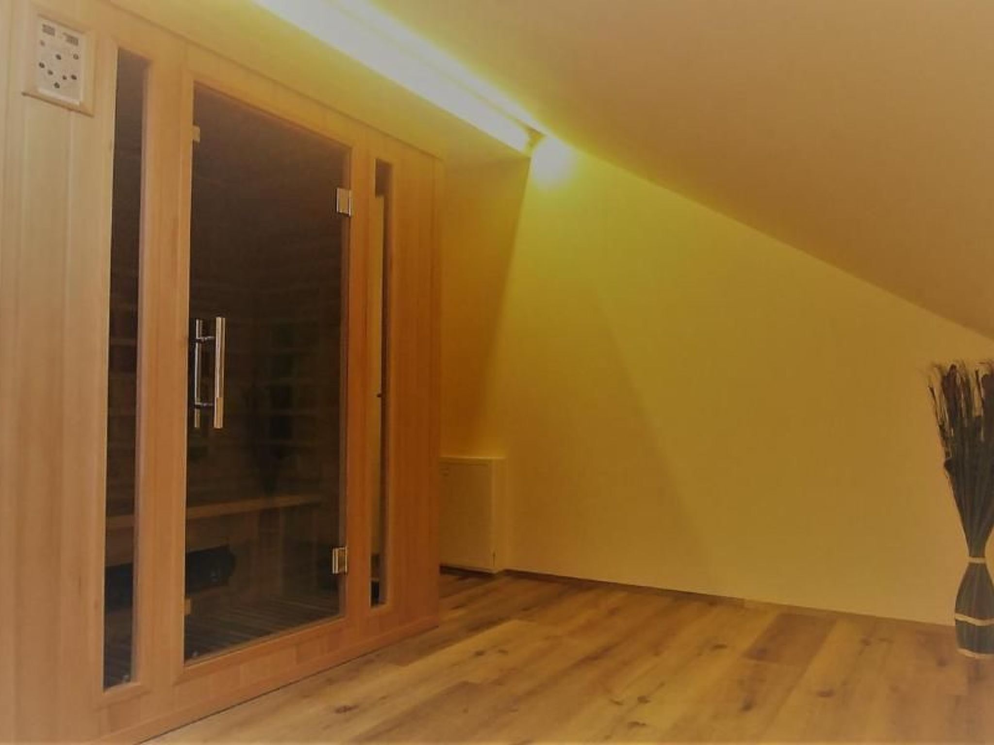 Ein Zimmer mit einem Holzschrank, einem Heizkörper und einer Vase auf dem Boden.
