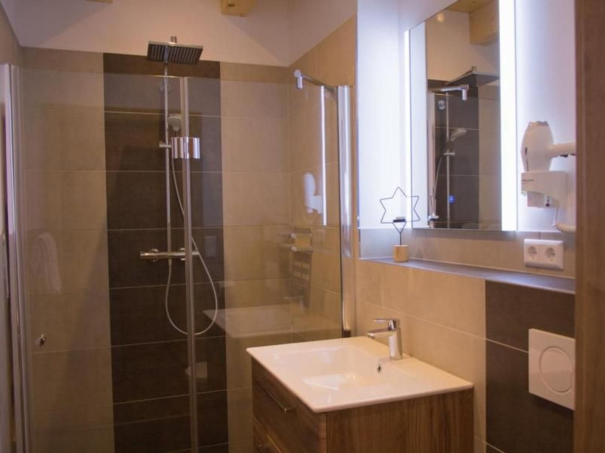 A modern bathroom with a glass-enclosed shower, a vanity with a sink, and a mirror.